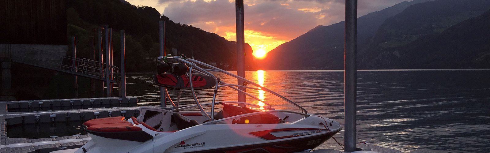Lancha amarrada a un muelle flotante al atardecer en un lago de montaña