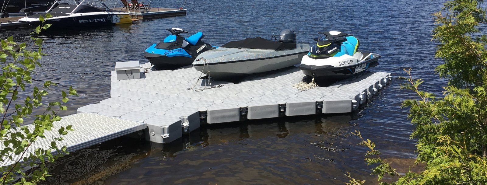 Lancha sobre un JetSlide y dos motos de agua sobre camas flotantes en un muelle Candock