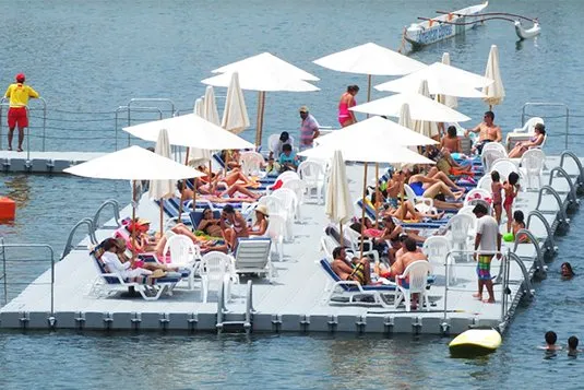 Solárium flotante Candock con reposeras y sombrillas lleno de bañistas