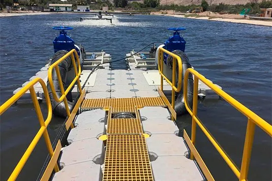 Plataforma flotante Candock con bombas, barandas amarillas y piso de rejilla en un proyecto minero