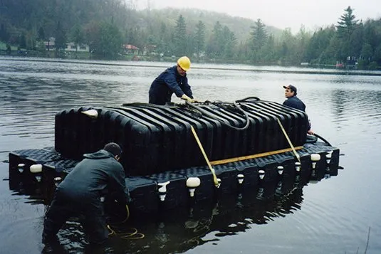 Operarios trasladando un tanque sobre una plataforma flotante Candock de cubos negros