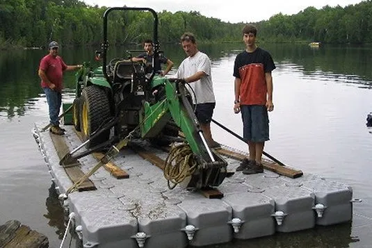 Tractor con retroexcavadora trasladado sobre una plataforma flotante Candock